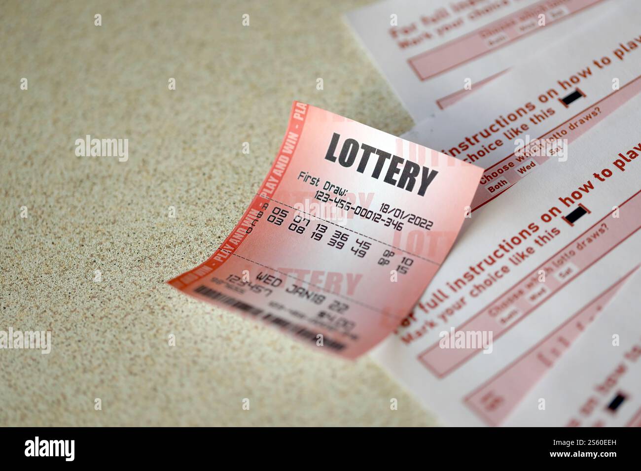 Billet de loterie rouge se trouve sur des feuilles de jeu roses avec des numéros pour marquer pour jouer à la loterie. Concept de jeu de loterie ou dépendance au jeu. Gros plan Banque D'Images