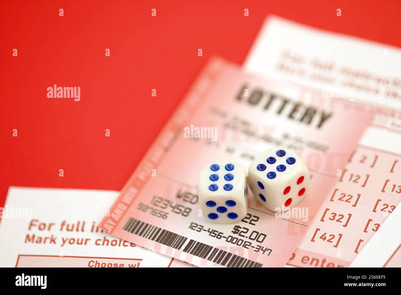 Billet de loterie rouge avec dés se trouve sur des feuilles de jeu roses avec des numéros pour marquer pour jouer à la loterie. Concept de jeu de loterie ou dépendance au jeu. Banque D'Images