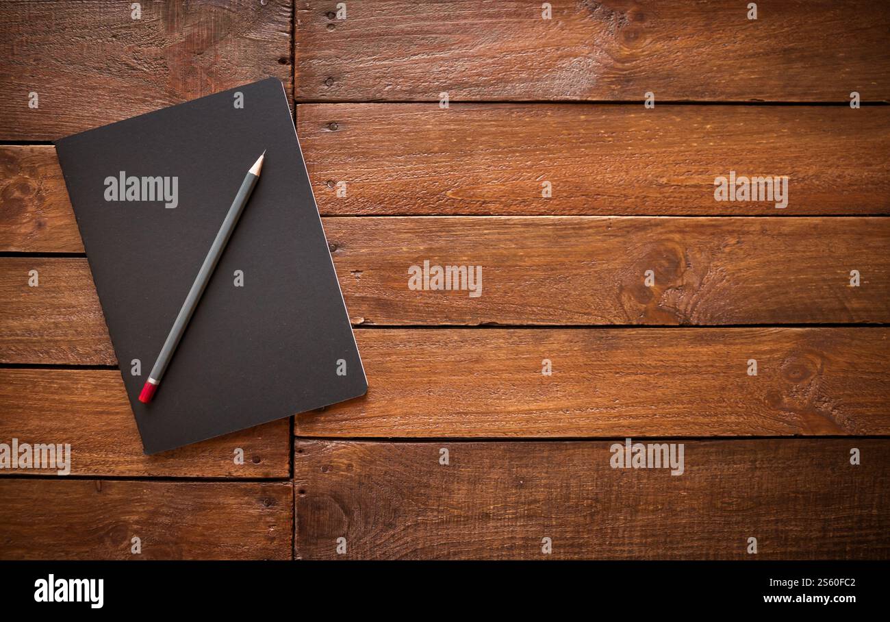 Cahier fermé et crayon sur une planche de bois vintage rustique. Cahier fermé et crayon sur une planche de bois rustique Banque D'Images