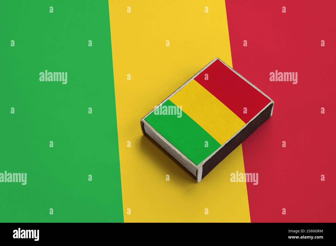 Le drapeau du Mali est représenté sur une boîte d'allumettes qui repose sur un grand drapeau. Le drapeau du Mali est représenté sur une boîte d'allumettes qui repose sur un grand drapeau Banque D'Images