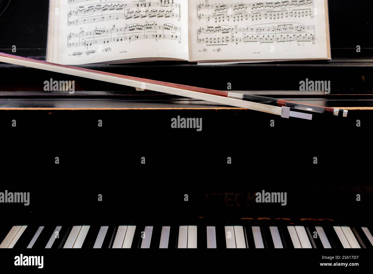 Un arc de violoncelle et un piano avec partition classique prêt pour un duo à jouer Banque D'Images