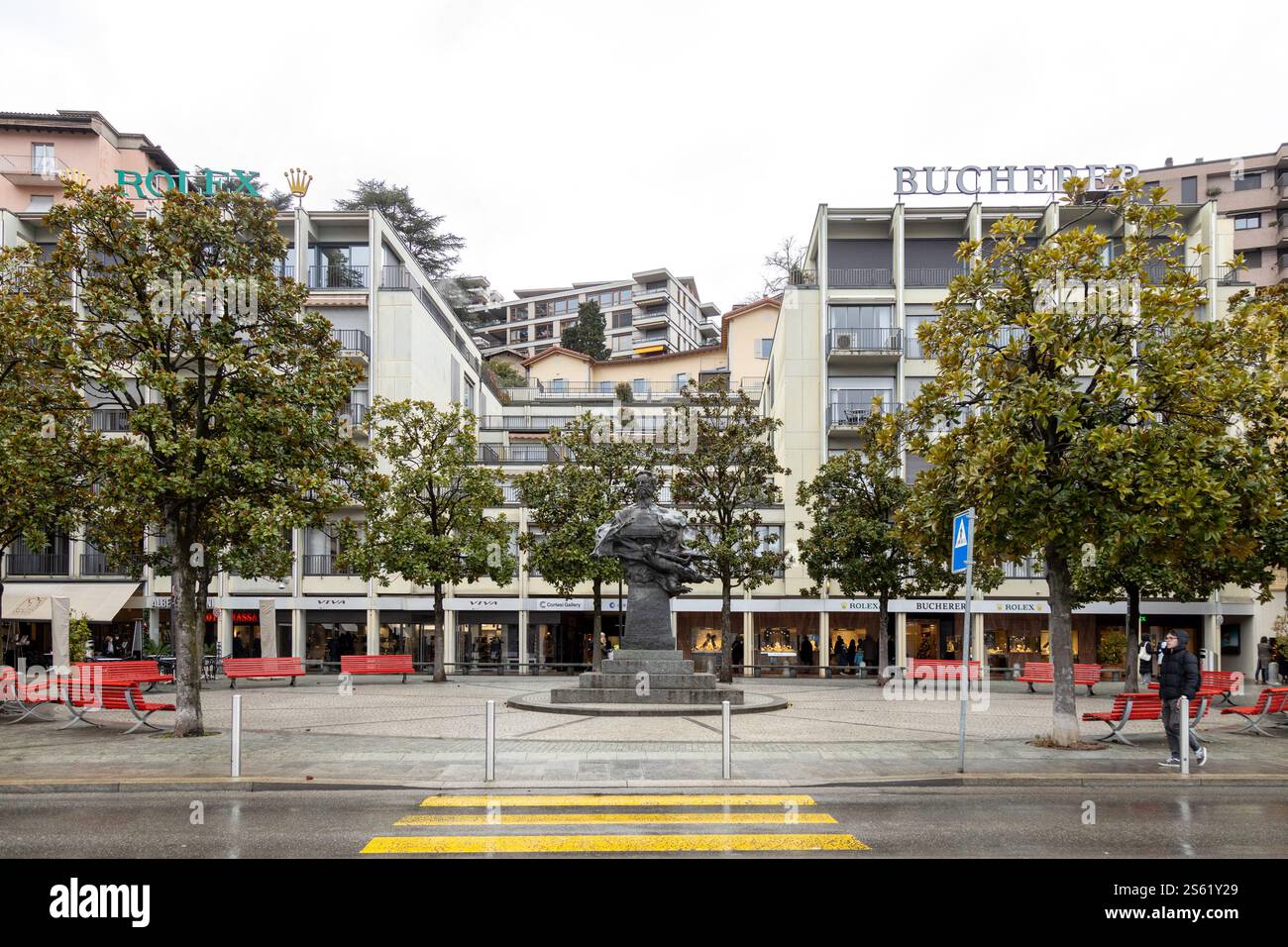 Lugano, Suisse - 22 décembre 2024 : Piazza Carlo Battaglini avec sa statue emblématique et ses bancs rouges Banque D'Images