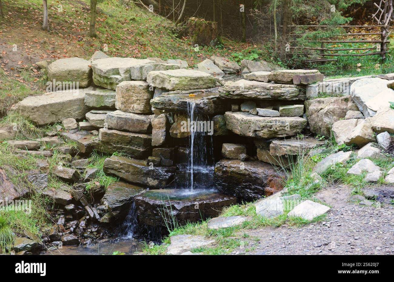 Gros plan d'une petite chute d'eau se déversant sur des rochers couverts de mousse dans le parc régional. Cascade de rivière faite à la main de petites pierres. Gros plan d'un petit Banque D'Images