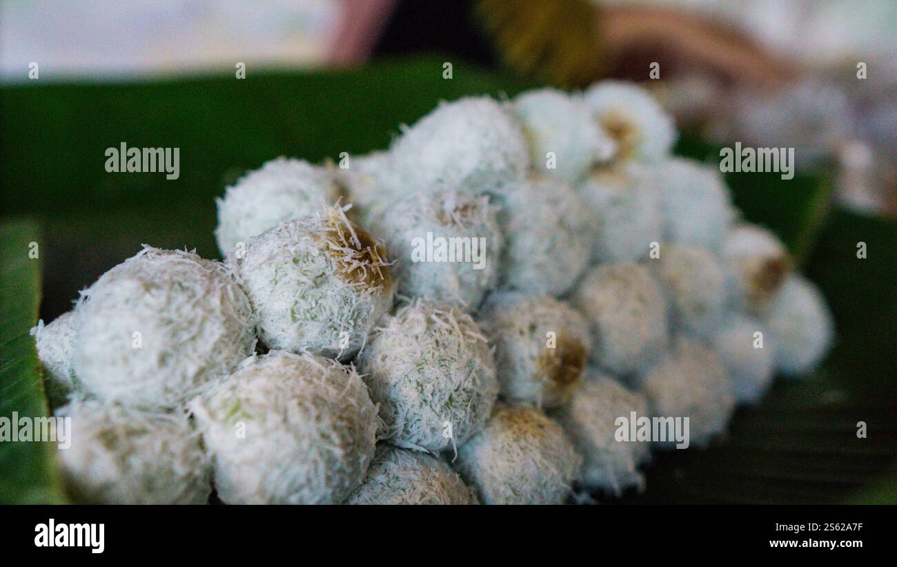 Un tas de bonbons klepon traditionnels indonésiens, recouverts de noix de coco râpée, sur des feuilles de bananier. Banque D'Images