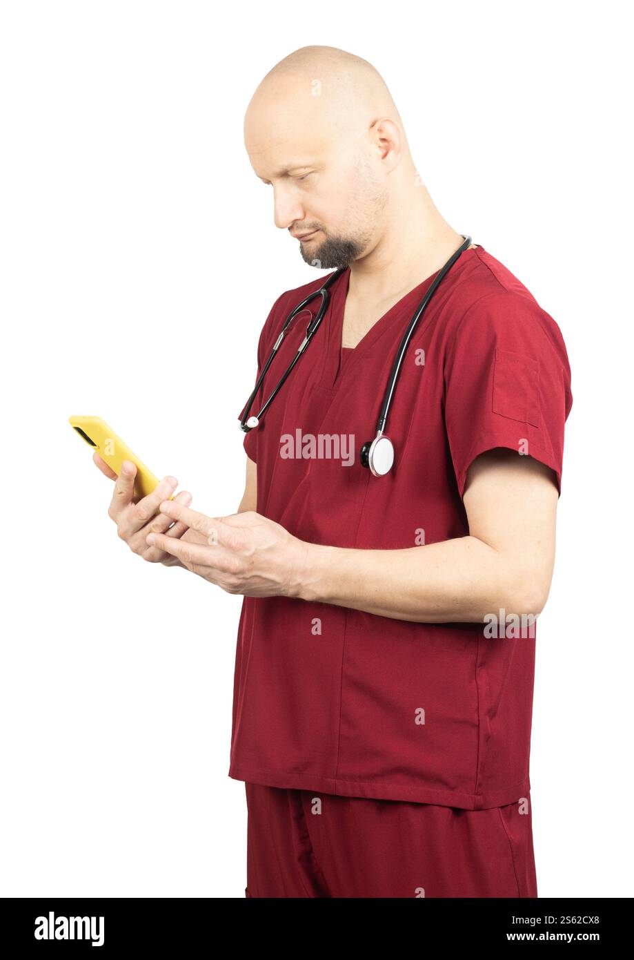 Un médecin chauve portant des gommages médicaux rouges et un stéthoscope autour du cou regarde un smartphone jaune. Banque D'Images