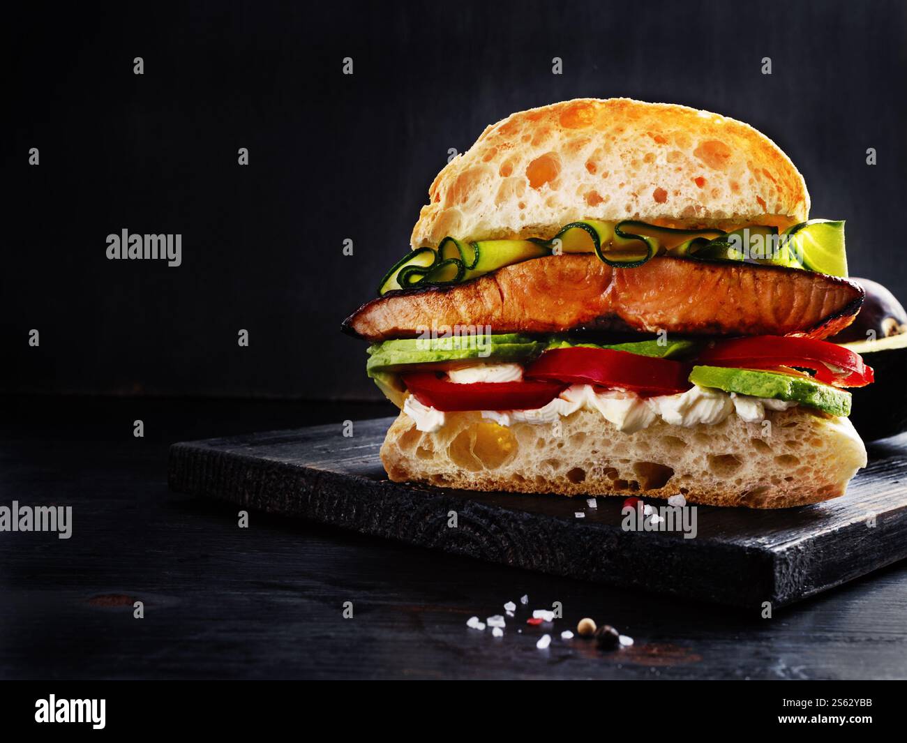 Sandwich ultime avec saumon grillé, fromage à la crème, avocat tranché et Seasonals sur planche de bois noir avec espace texte libre. Banque D'Images