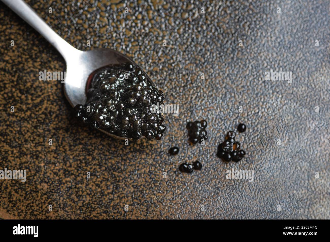 Caviar d'esturgeon noir sur cuillère sur fond brun foncé gros plan, espace de copie. Esturgeon sauvage ou caviar de béluga. Banque D'Images