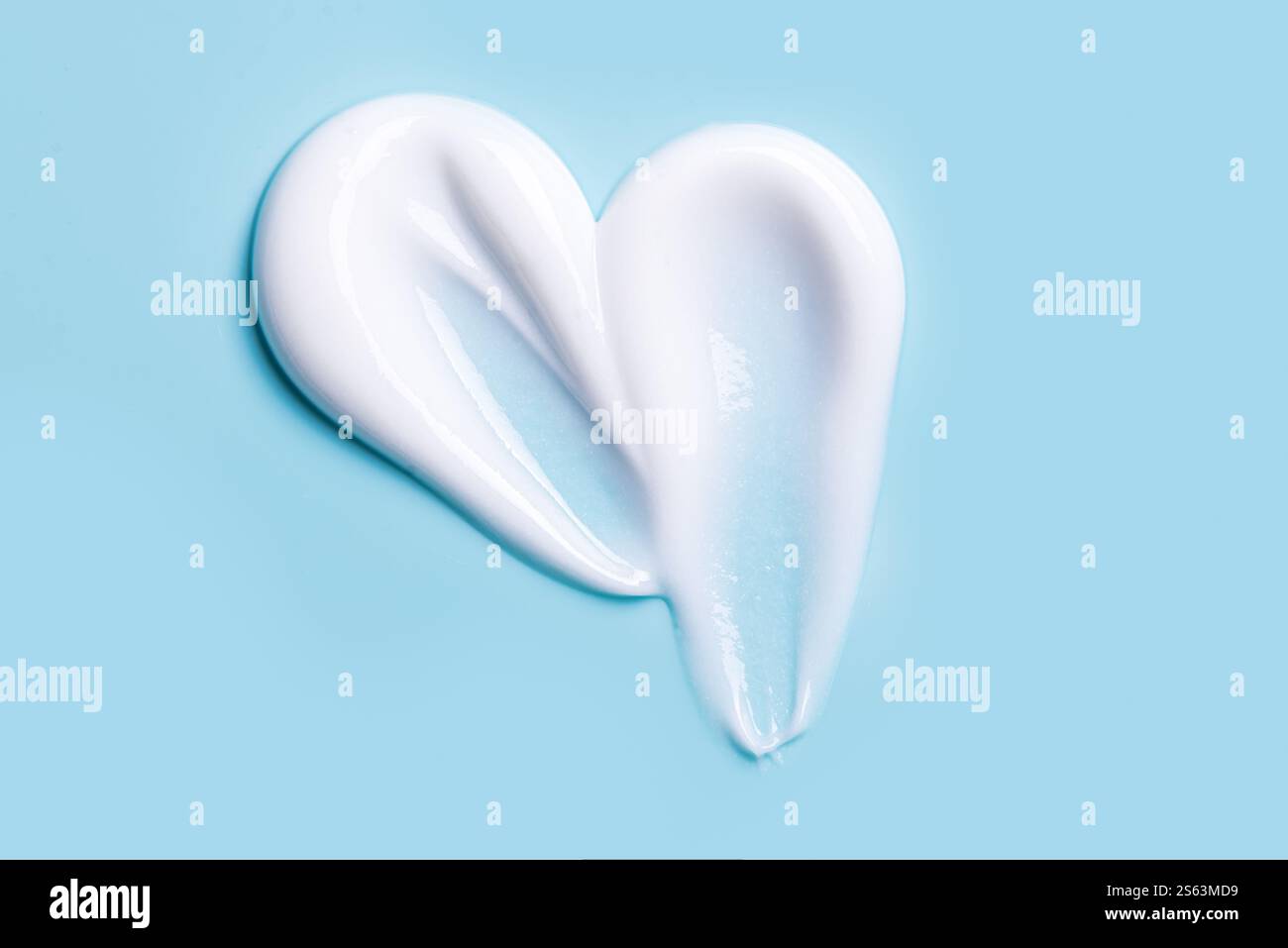 Texture de crème cosmétique. Frottis de lotion. Échantillon de gel de soins de la peau crémeux blanc sur fond bleu. Banque D'Images