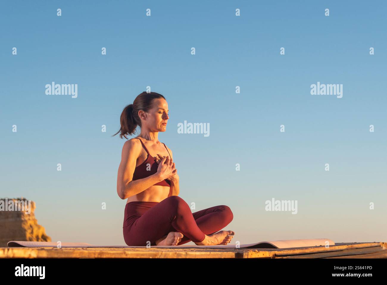 belle femme adulte moyenne assise méditant au lever du soleil Banque D'Images