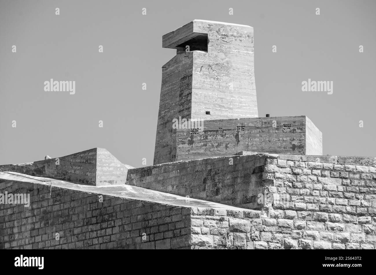 Un grand bâtiment en briques avec une petite fenêtre sur le dessus. Le bâtiment est entouré d'un mur de briques Banque D'Images
