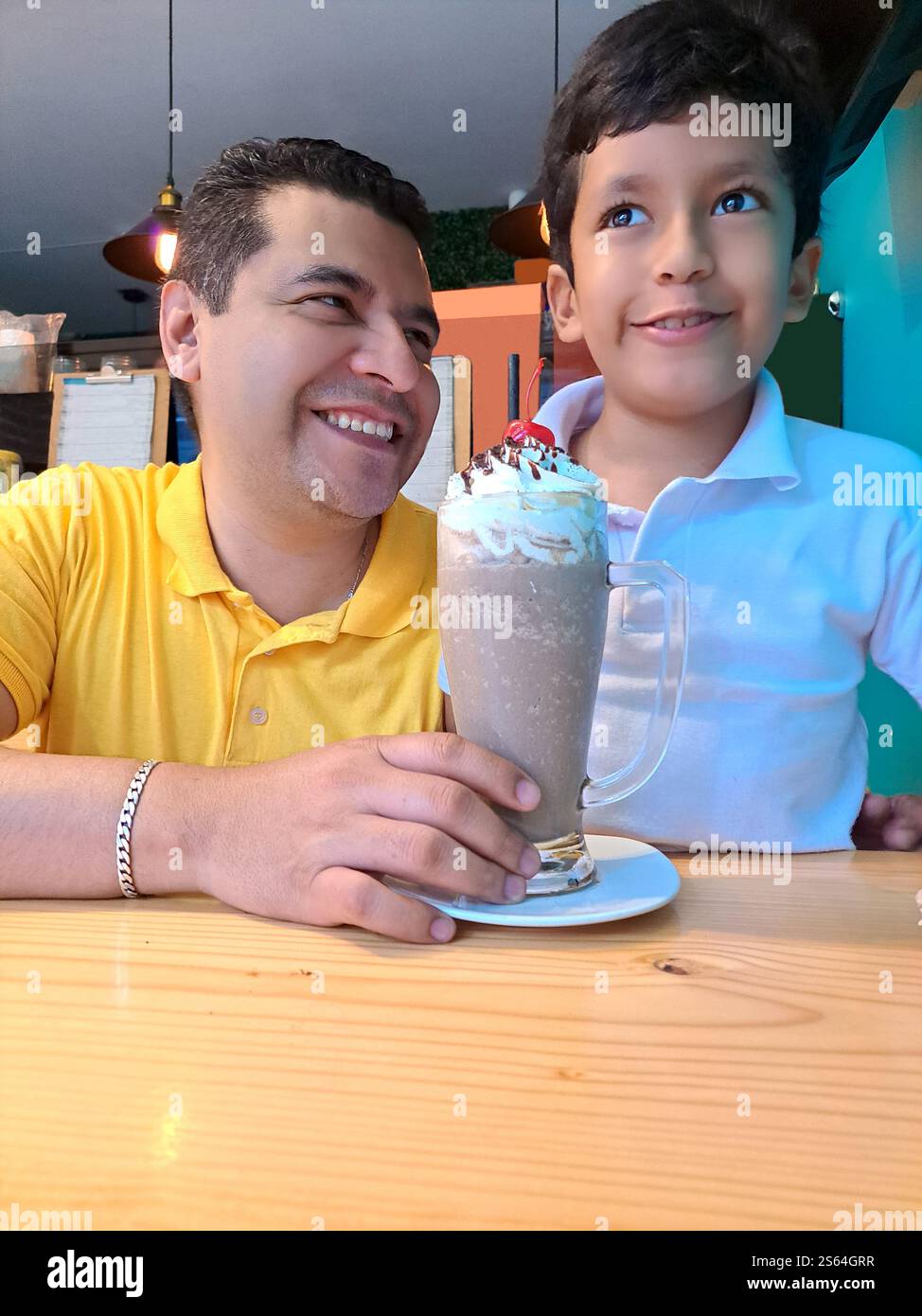 Père célibataire divorcé avec son fils de 9 ans ont un milk-shake dans un café passer du temps de qualité joyeusement célébrer la fête des pères Banque D'Images