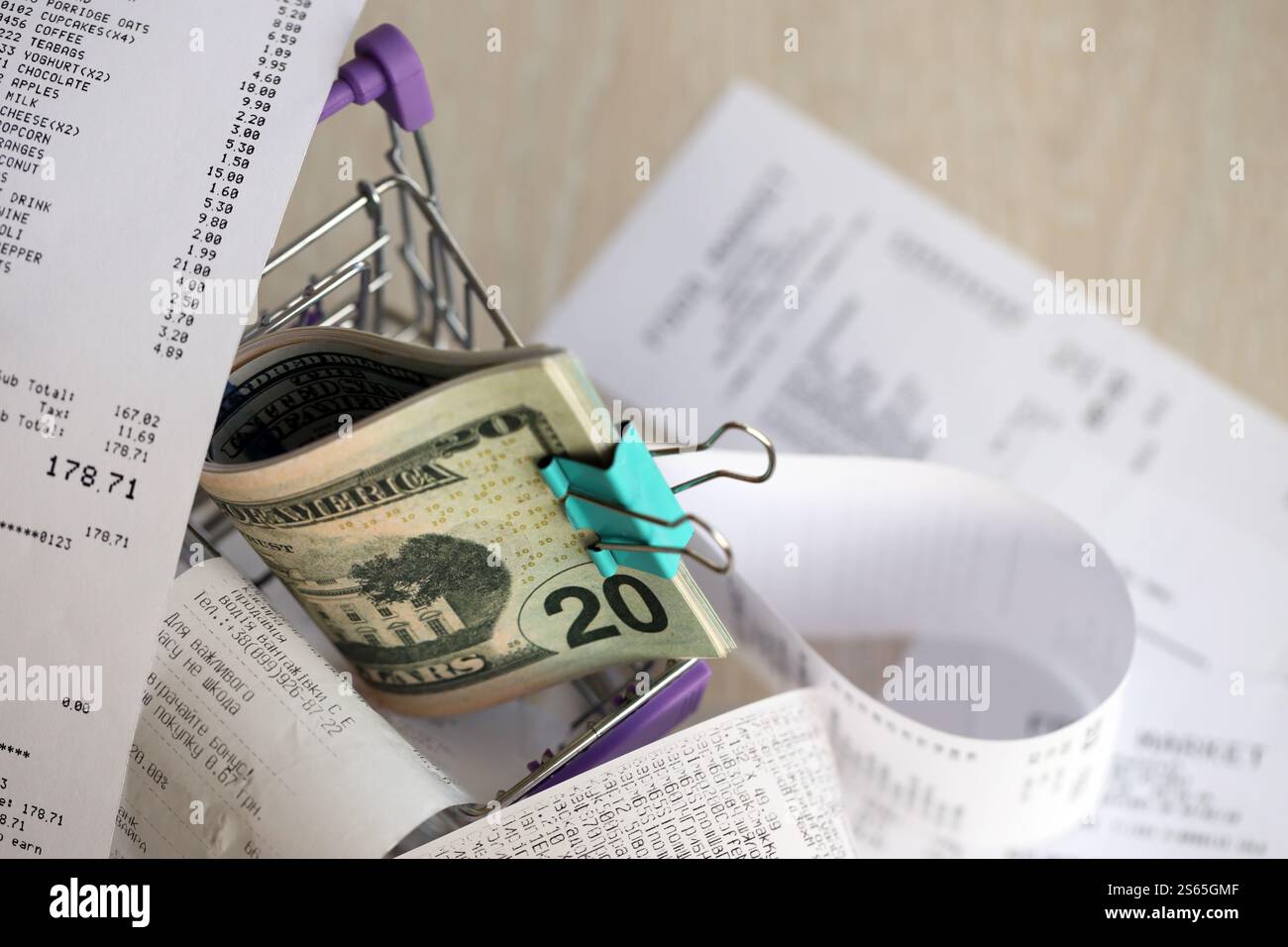 Paquet de dollars AMÉRICAINS dans le chariot de shopping entouré de nombreux reçus papier de près. Paquet de dollars US dans le chariot de shopping entouré de beaucoup de papier Banque D'Images