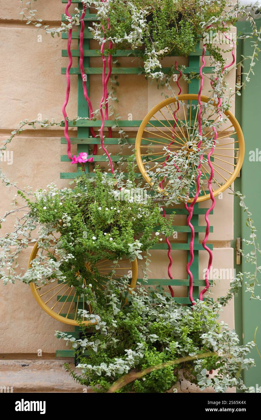 Décoration objet d'art urbain de roues de vélo et fleurs élégantes colorées sur le mur. Décoration objet d'art urbain de roues de vélo et de fleurs sur Banque D'Images