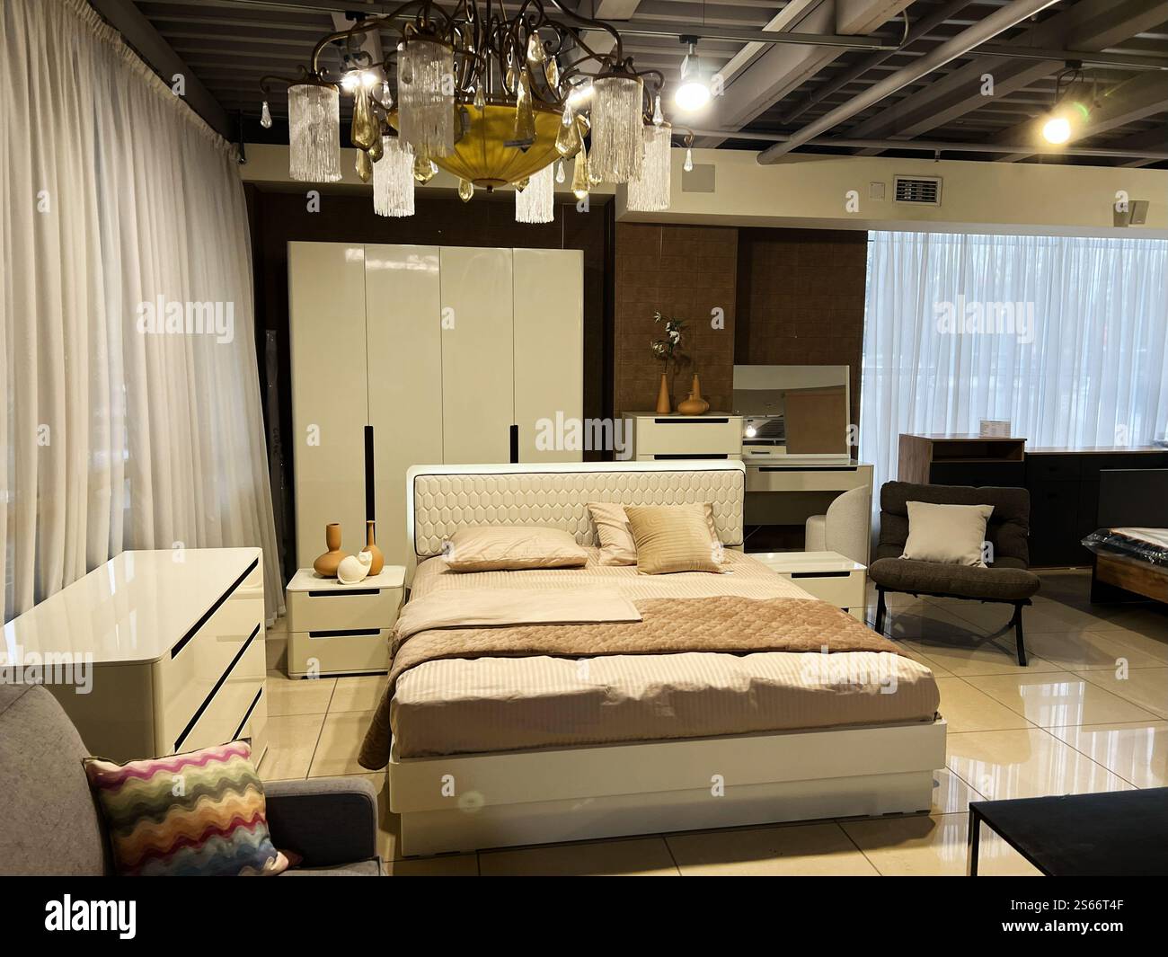 Une chambre moderne magnifiquement conçue avec des meubles blancs élégants, des accents décoratifs et un éclairage doux. L'espace dégage une vib épurée et minimaliste Banque D'Images