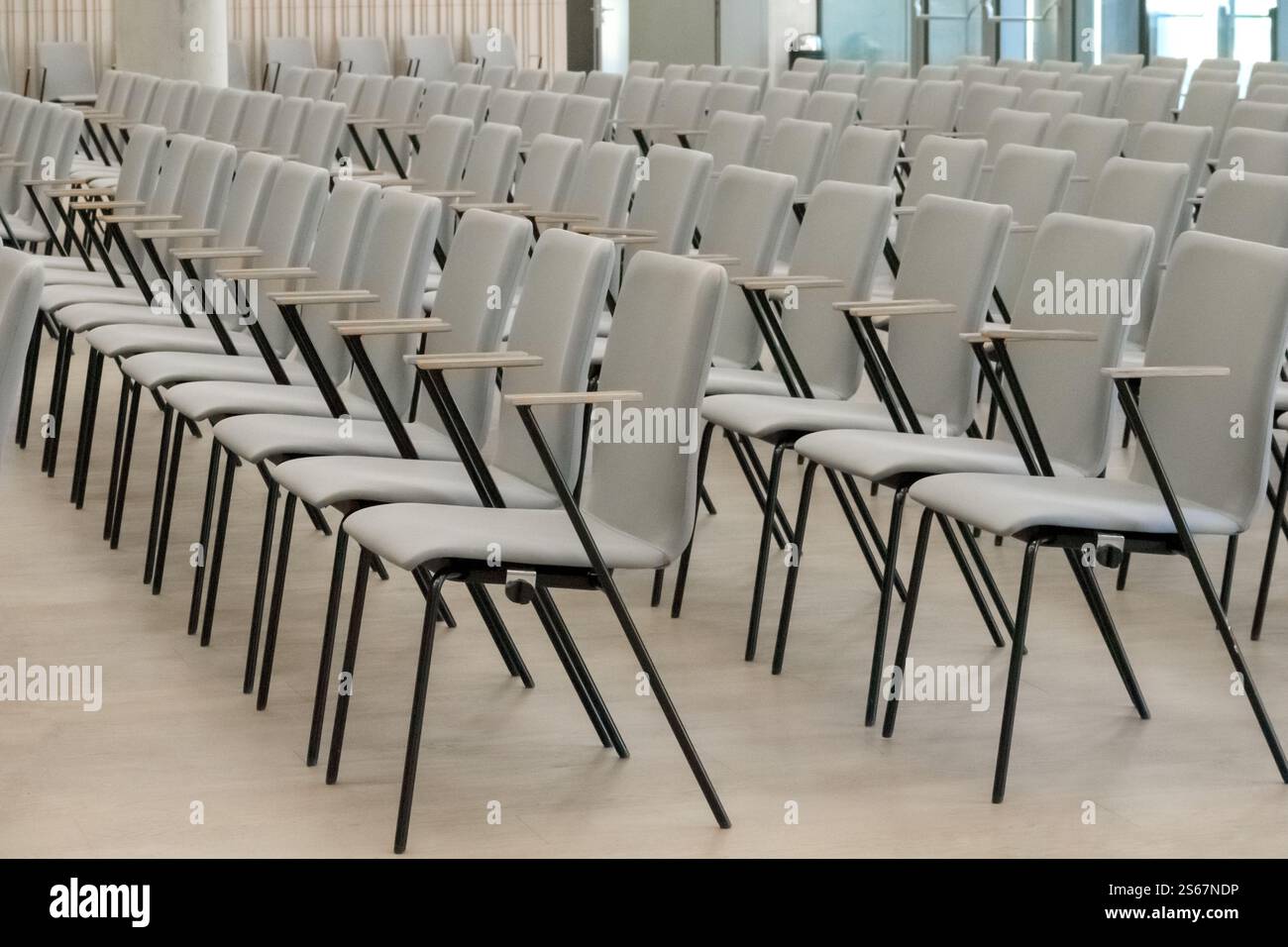 Un fragment vide d'une salle de conférence ou d'un auditorium avec des rangées de chaises grises avec des bras en bois. Banque D'Images