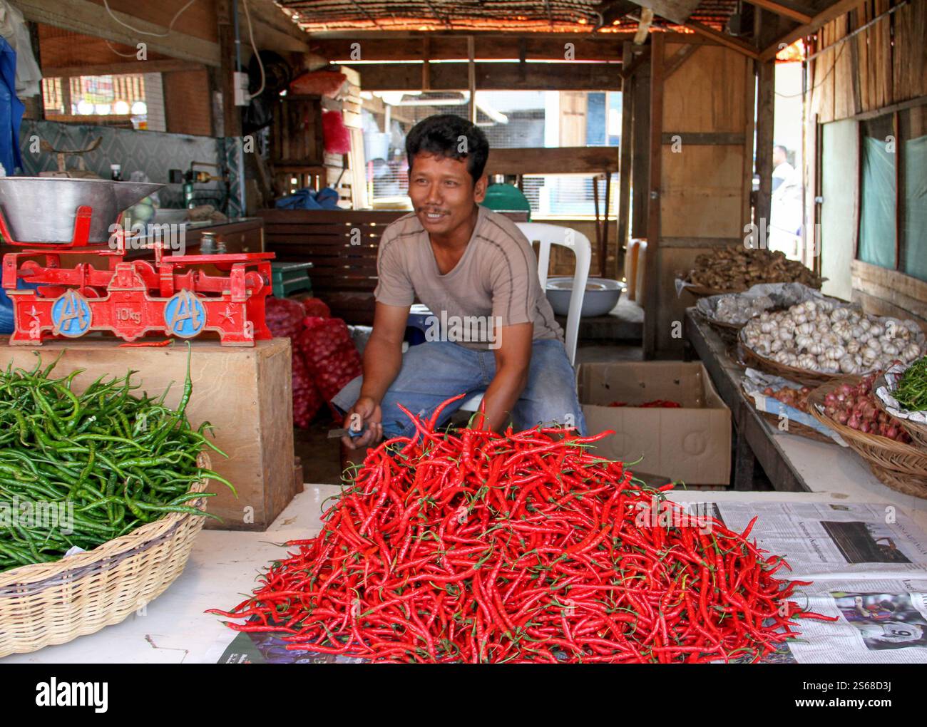 Un homme indonésien vendant des piments verts et rouges frais dans un marché traditionnel à Bukittinggi, Sumatra Ouest, Indonésie. Banque D'Images