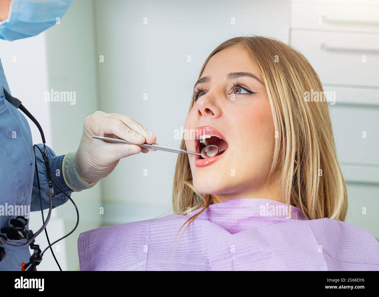 Dentiste utilisant miroir dentaire et explorateur pour examiner les dents du patient dans la clinique dentaire moderne Banque D'Images