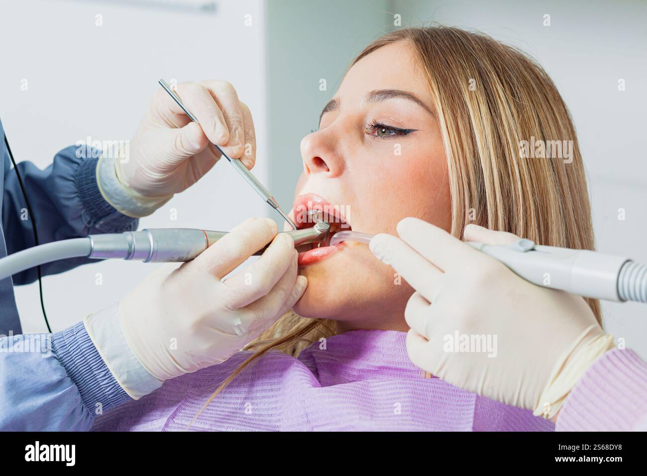 Dentiste pratiquant une intervention dentaire à l'aide d'un équipement spécialisé sur un patient en clinique dentaire Banque D'Images