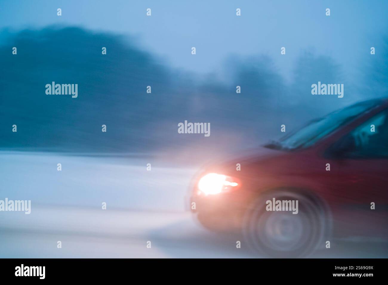Voiture conduisant dans de mauvaises conditions météorologiques avec de la neige sur l'autoroute de nuit, long exposition dans l'appareil photo flou de mouvement Banque D'Images