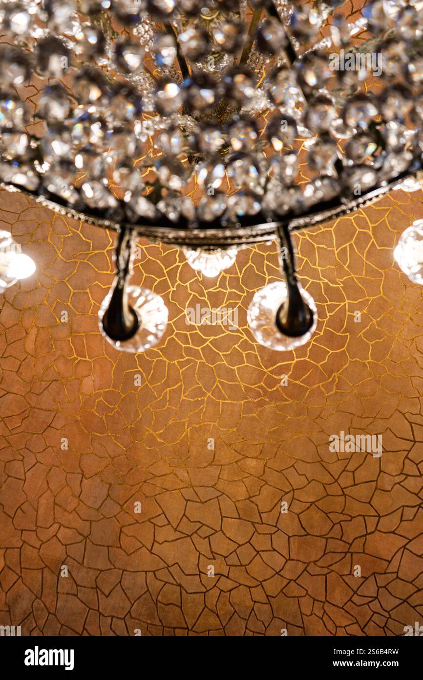 Intérieur de la Casa Batlló, mettant en valeur un lustre élégant et un papier peint or complexe, incarnant le design moderniste signature de Gaudí. Banque D'Images