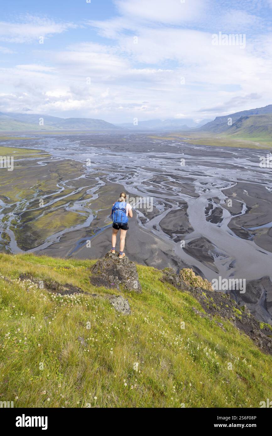 Randonneur, jeune femme sur une colline, vue sur des terres alluviales, rivière sinueuse, Dimonarhellir, SuÃ°urland, Islande, Europe Banque D'Images
