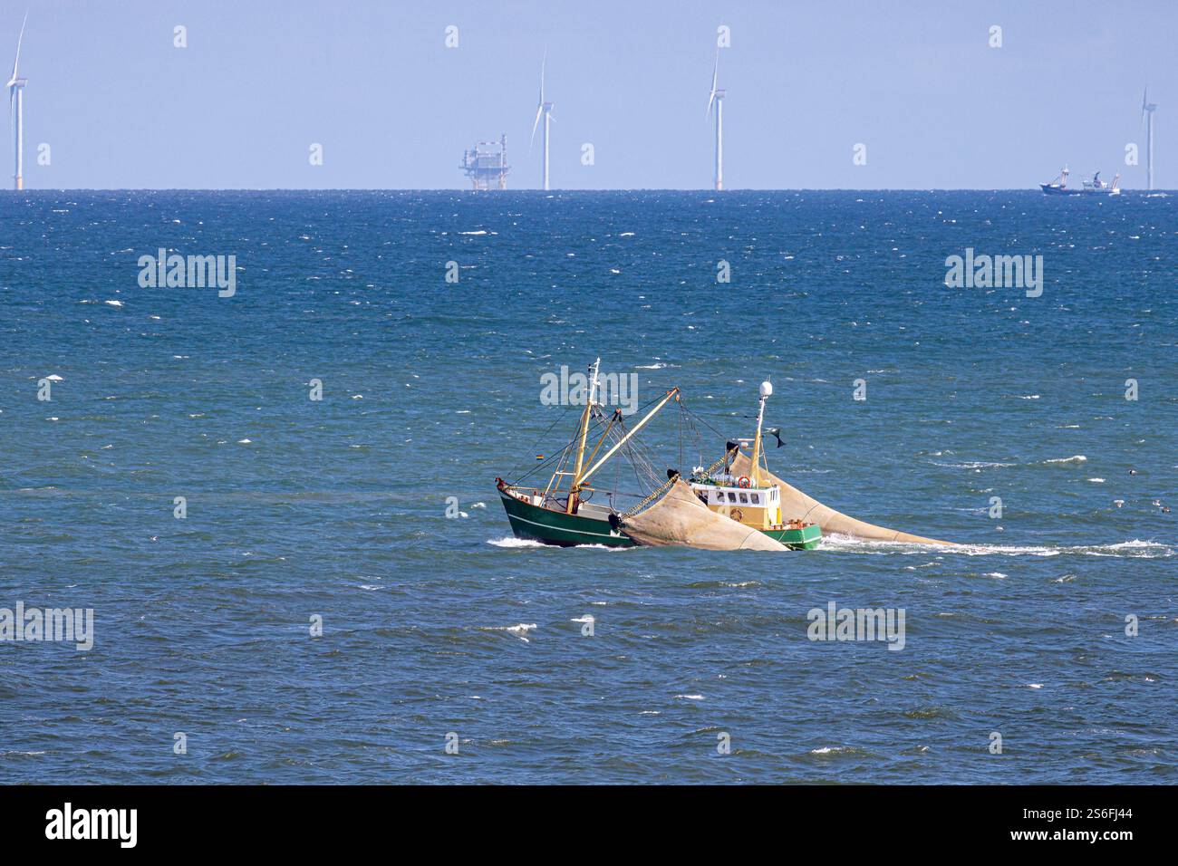 Un bateau de pêche avec des filets traînants levés devant un parc éolien en mer du Nord près d'Egmond aan Zee Banque D'Images