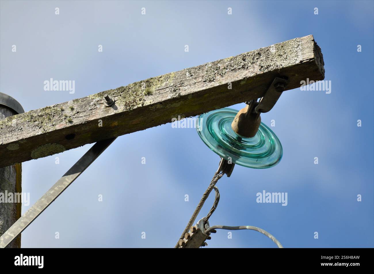 Regardez un isolant en verre vert reliant une ligne électrique à un poteau de service. Gros plan. Banque D'Images