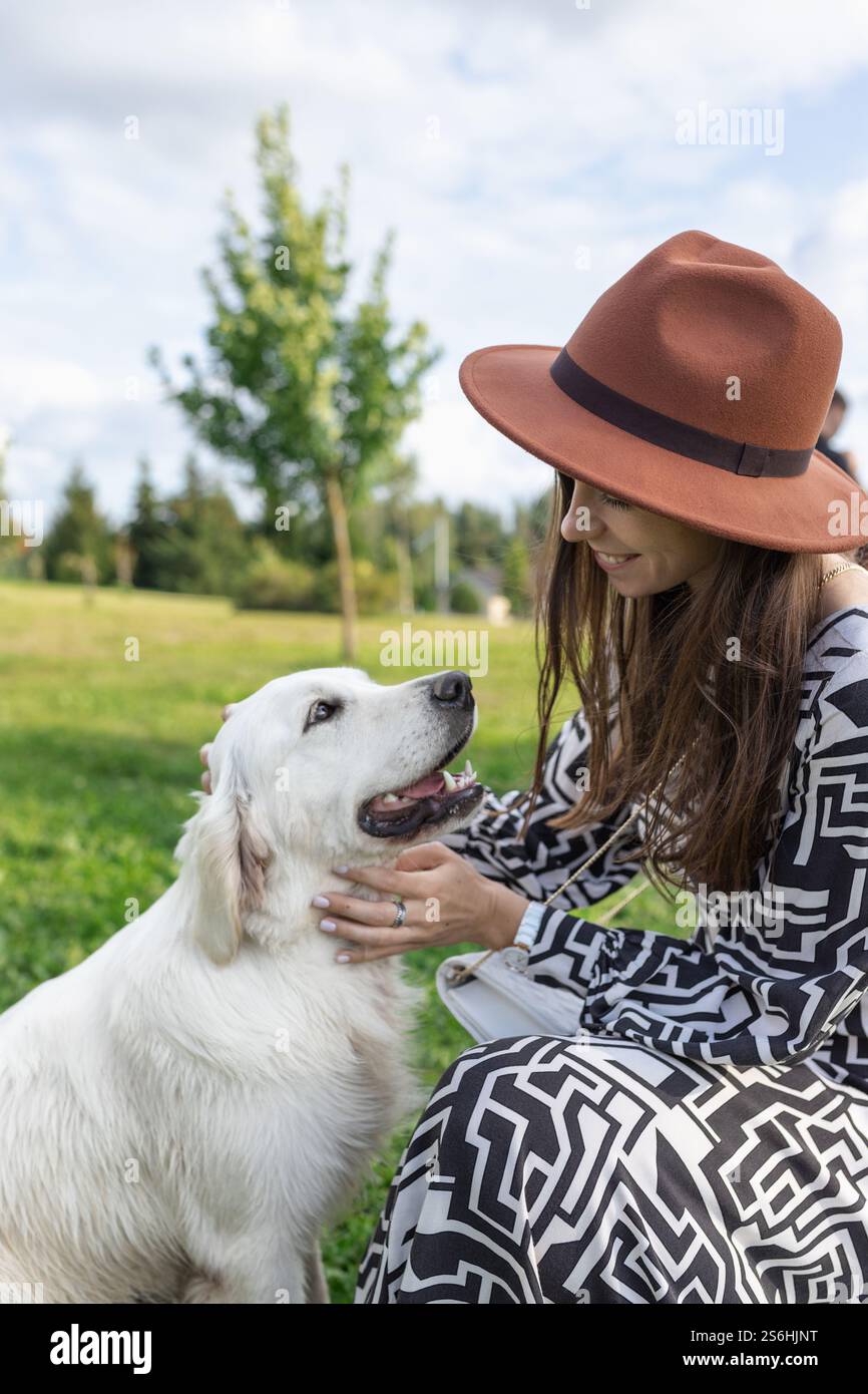 Jeune femme adulte assise avec et souriant au chien Golden retriever Banque D'Images