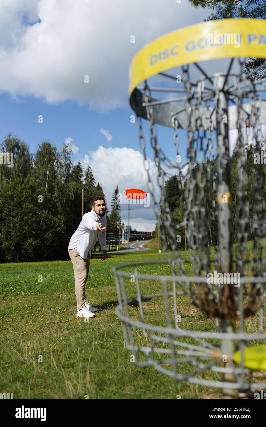 Beau jeune homme adulte jouant au disc golf par une journée ensoleillée Banque D'Images