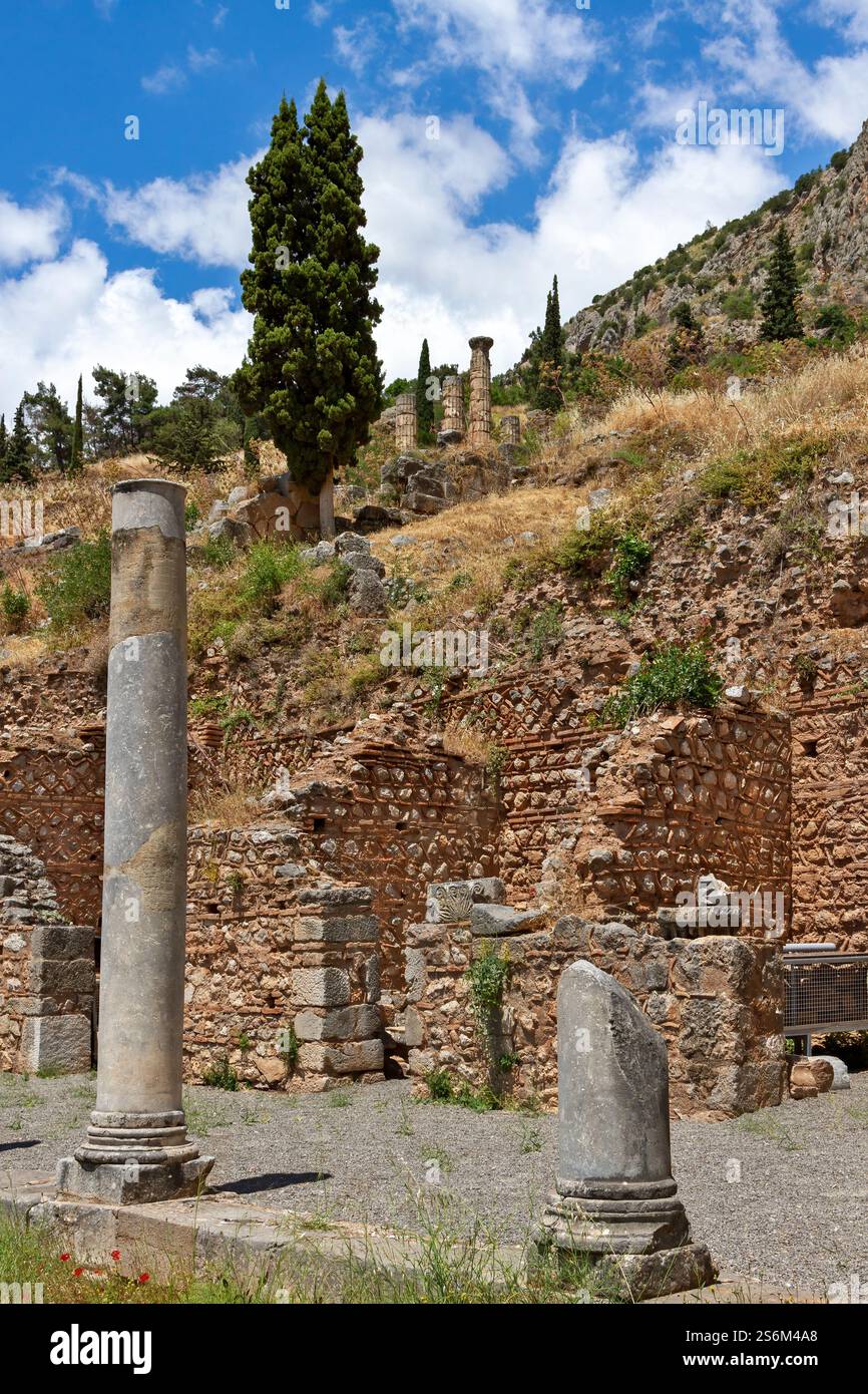 Ruines de l'ancien site archéologique de Delphes, en Grèce, avec des colonnes altérées et des pierres sur un paysage montagneux et un ciel vibrant Banque D'Images