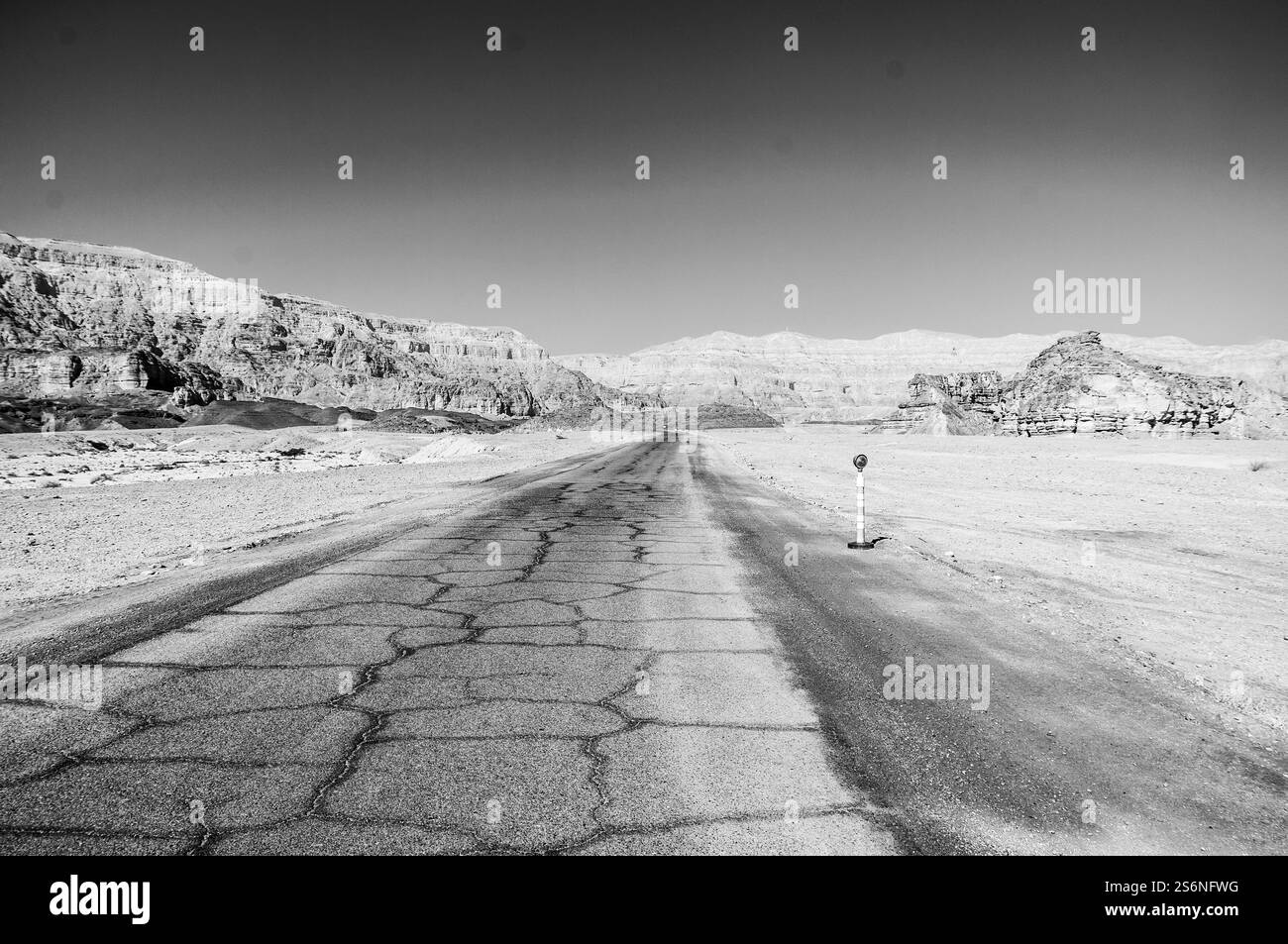 Une route désolée avec quelques rochers et un panneau. La route est vide et le ciel est dégagé Banque D'Images