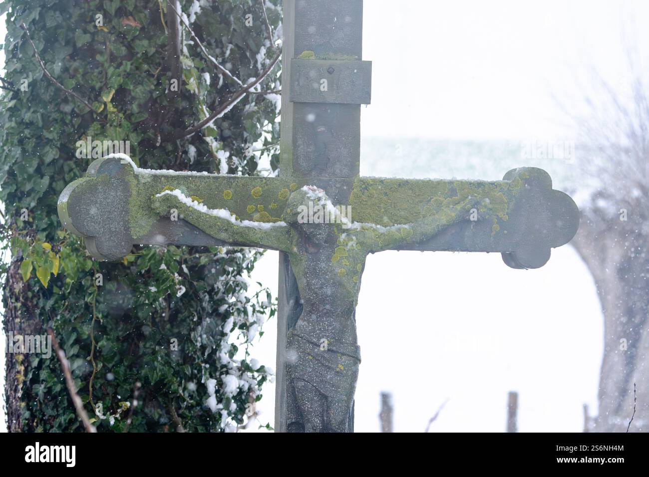 Une croix avec une statue de Jésus dessus est couverte de neige. La neige recouvre la statue de Jésus et la croix, lui donnant une apparence sereine et paisible Banque D'Images