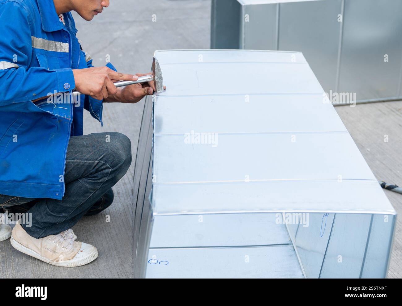 Technicien pliant bord de tôle avec maillet dans l'atelier. Banque D'Images