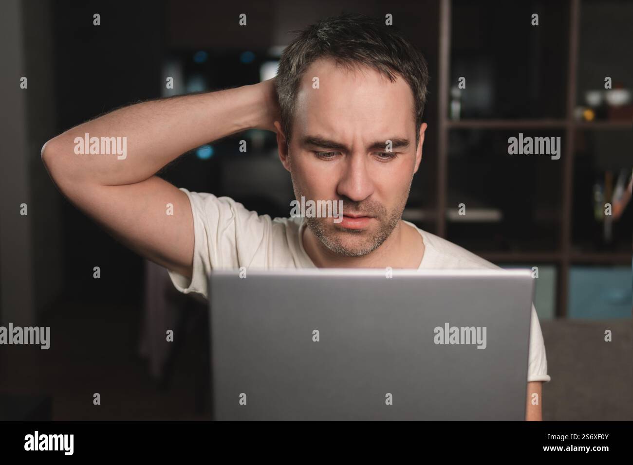 Jeune homme concentré gars tout en travaillant sur ordinateur portable et en regardant l'écran de pc pendant le travail à distance du bureau à domicile, surmenage homme se sentant fatigué, proche Banque D'Images