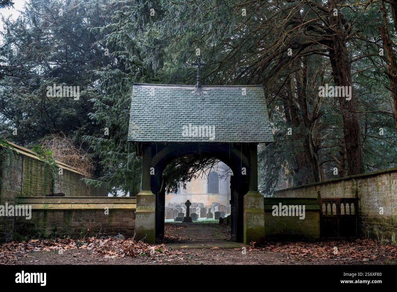 Lychgate entrant dans l'église All Saints dans la brume hivernale et le gel. Honington, Warwickshire, Angleterre Banque D'Images