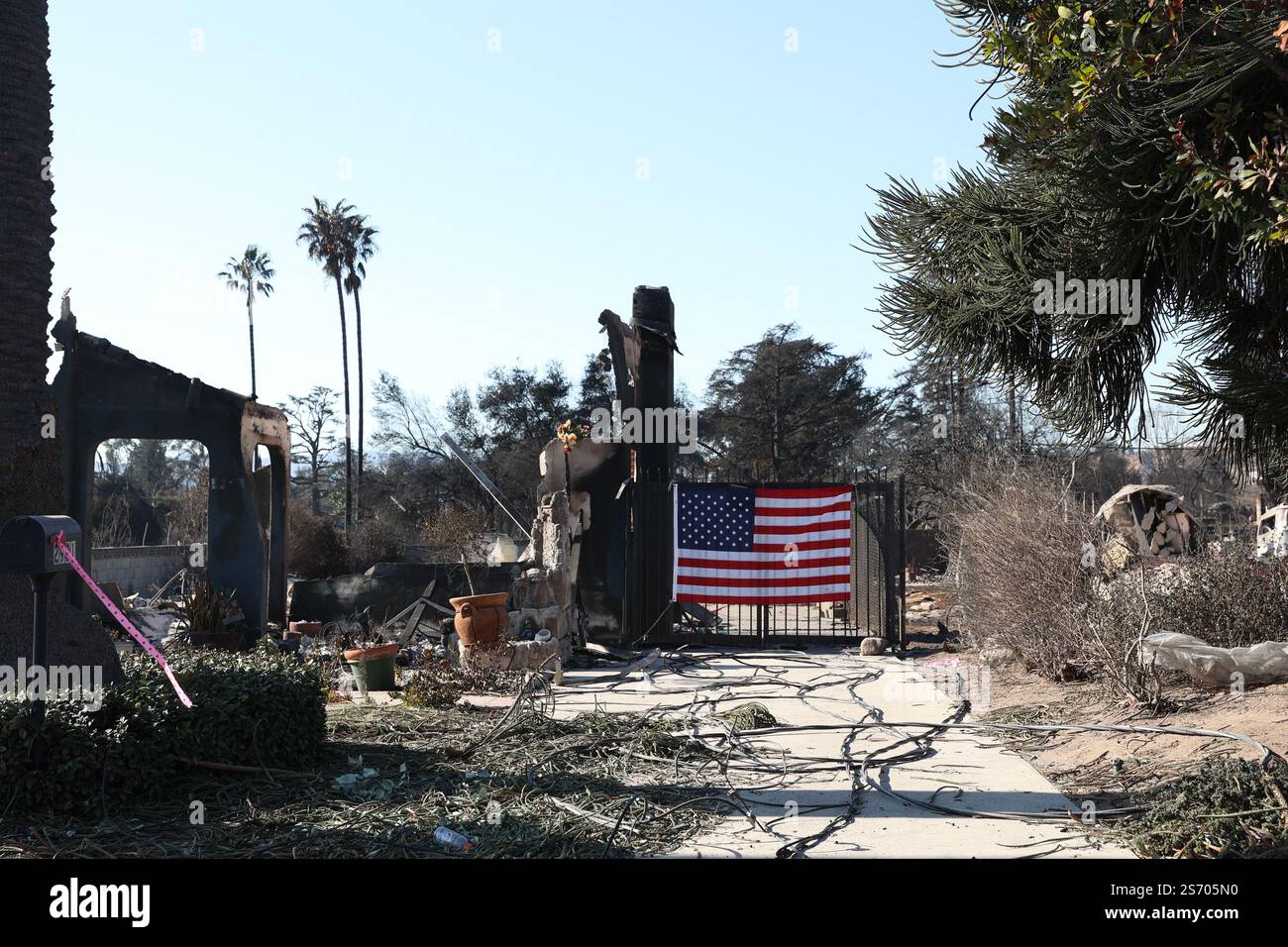 Los Angeles, États-Unis. 16 janvier 2025. Une maison brûlée avec un drapeau américain sur la porte après le feu d'Eaton. Zones sinistrées dans les villes de Pasadena et Altadena après le passage de l’incendie d’Eaton au nord-est de Los Angeles qui a débuté le mardi 07 janvier 16 janvier 2025 à Los Angeles. Photo Christophe Michel/ABACAPRESS. COM Credit : Abaca Press/Alamy Live News Banque D'Images