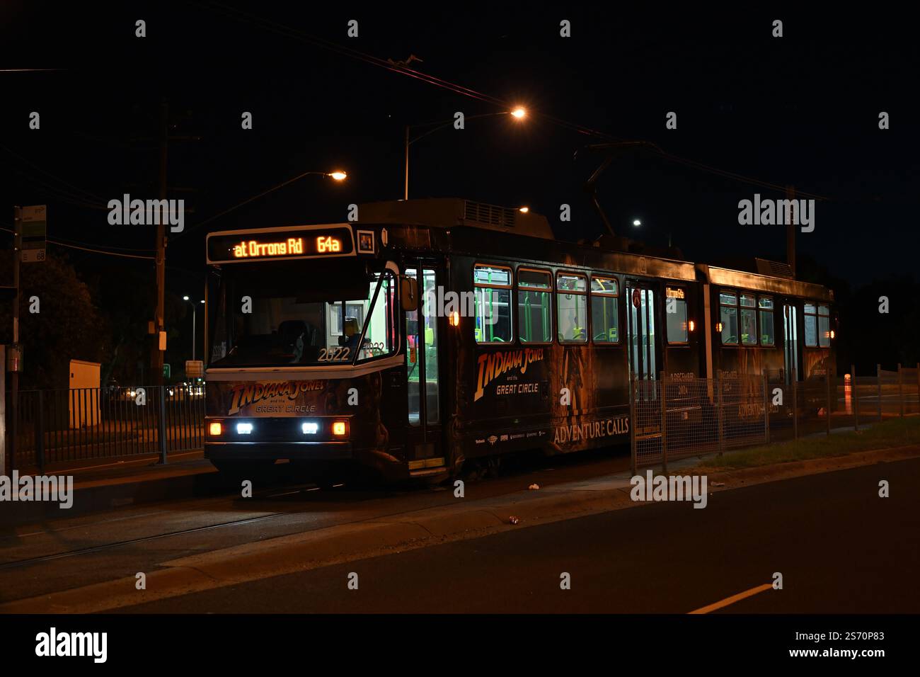 Le tramway de Melbourne de classe B, couvert de publicité pour Indiana Jones et le jeu vidéo Great Circle, s'arrêta au bout de la ligne la nuit Banque D'Images Le tramway de Melbourne de classe B, couvert de publicité pour Indiana Jones et le jeu vidéo Great Circle, s'arrêta au bout de la ligne la nuit Banque D'Images