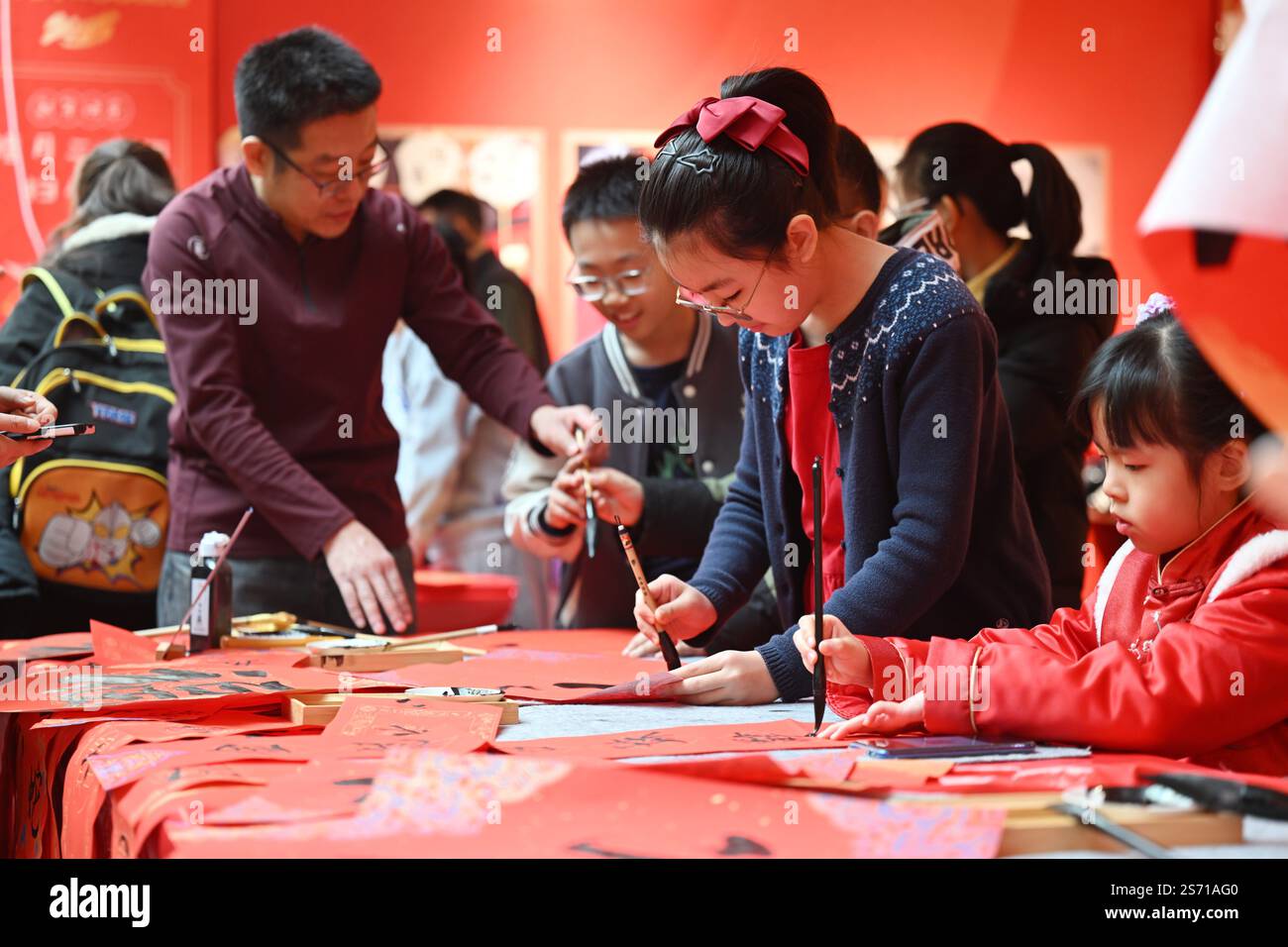 Tianjin. 18 janvier 2025. Les enfants écrivent des couplets du Festival du printemps lors d'une foire du temple des enfants au Centre de la jeunesse et des enfants à Tianjin, au nord de la Chine, le 18 janvier 2025. L'événement pour enfants de trois jours a débuté samedi à Tianjin pour accueillir le nouvel an lunaire chinois en présentant le folklore du patrimoine culturel immatériel, des spectacles et des plats traditionnels. Crédit : Li Ran/Xinhua/Alamy Live News Banque D'Images