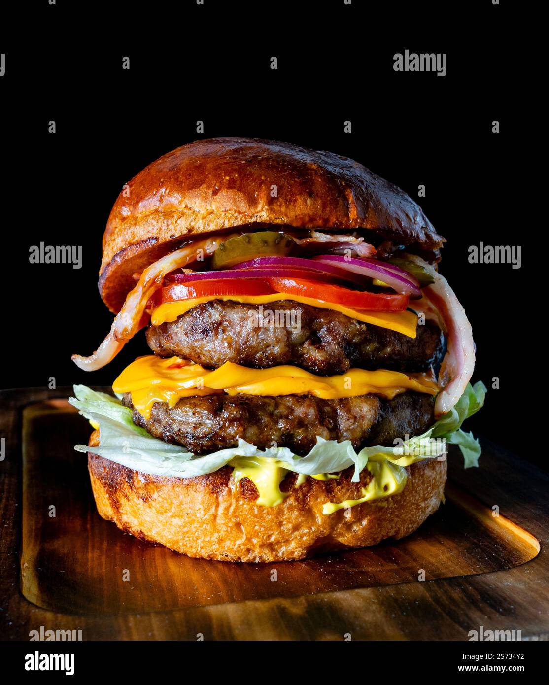 Ce hamburger gastronomique se compose de deux viandes de bœuf juteuses garnies de fromage cheddar, de laitue croustillante, de tomates tranchées, d'oignons rouges et de bacon fumé, toutes les encas Banque D'Images