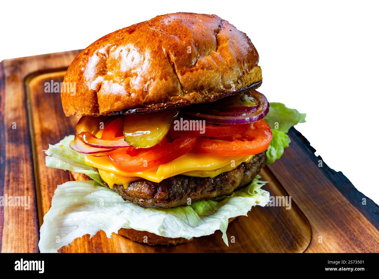Un hamburger gastronomique est posé sur une planche de bois, avec une galette juteuse recouverte de laitue fraîche, tomate, cornichons, fromage et oignon rouge, le tout inclus dans un Banque D'Images