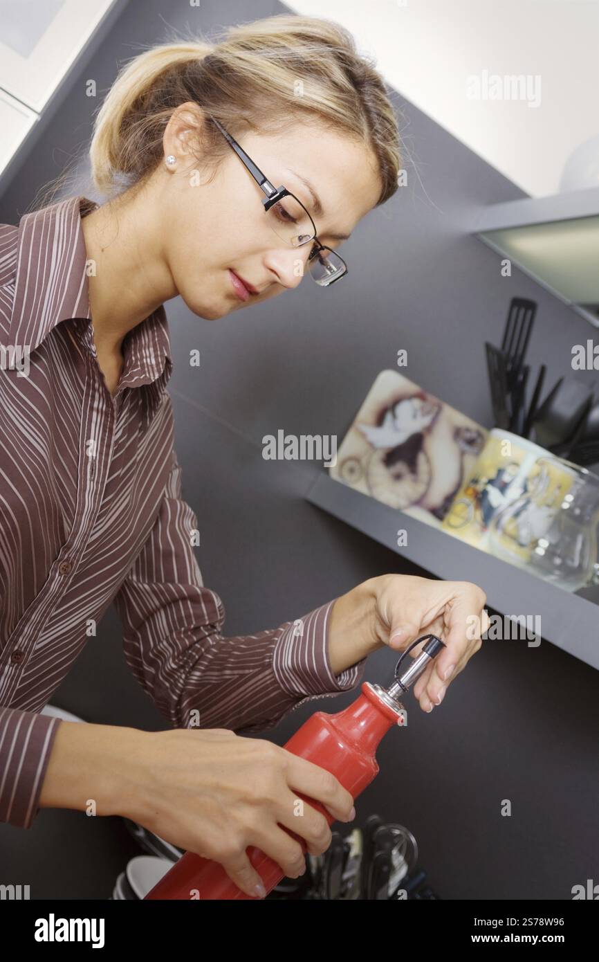Jeune femme blonde cuisinant dans une cuisine moderne, Moscou, Fédération de Russie Banque D'Images