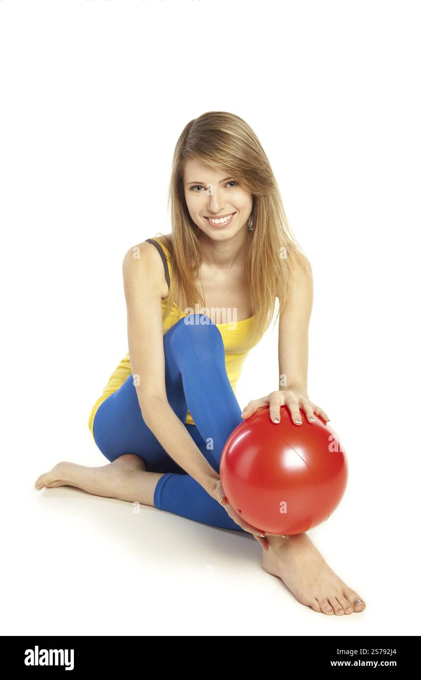Jolie jeune femme blonde souriante en vêtements sportifs tenant la balle rouge, Fédération de Russie Banque D'Images