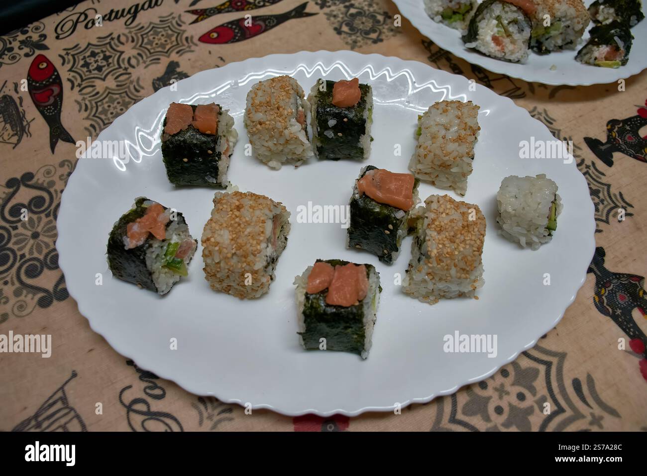 Une assiette de sushis maison avec des rouleaux assortis préparés avec des ingrédients frais. Les rouleaux sont présentés sur une plaque blanche, présentant une variété Banque D'Images