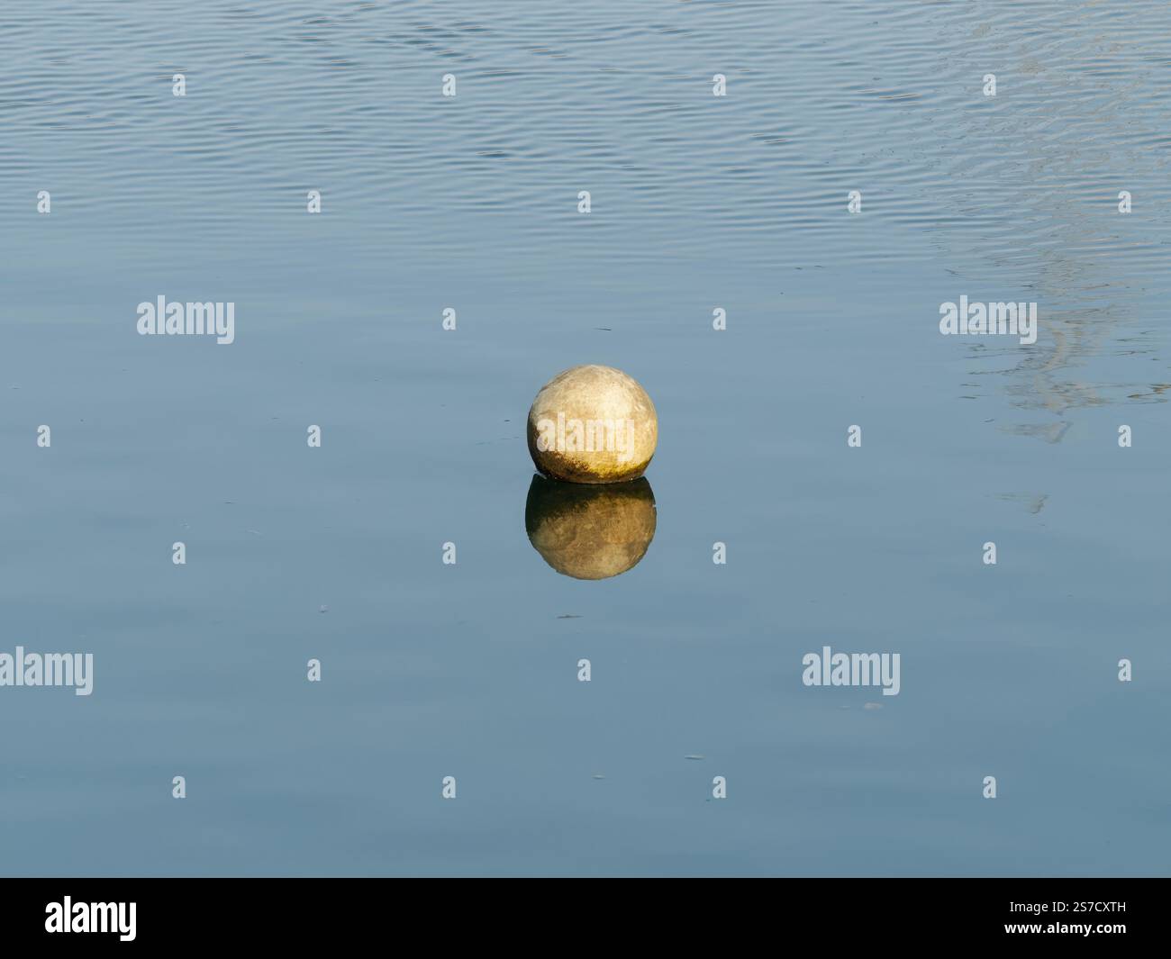 Boule jaune flottante se reflète paisiblement sur une surface de lac calme Banque D'Images