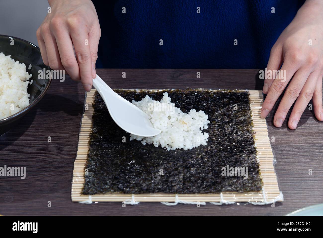 Une femme asiatique étalant du riz à sushi cuit sur une feuille de nori (algues comestibles) pour faire Kimchi Gimbap (Kimbap) - un plat populaire sud-coréen. ROYAUME-UNI Banque D'Images