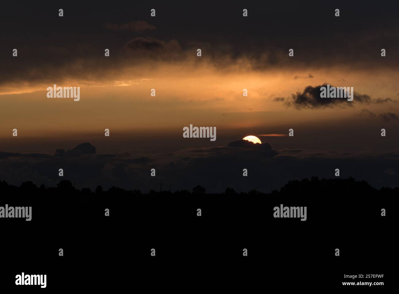 Coucher de soleil dramatique, noir et jaune, soleil presque caché derrière les nuages Banque D'Images