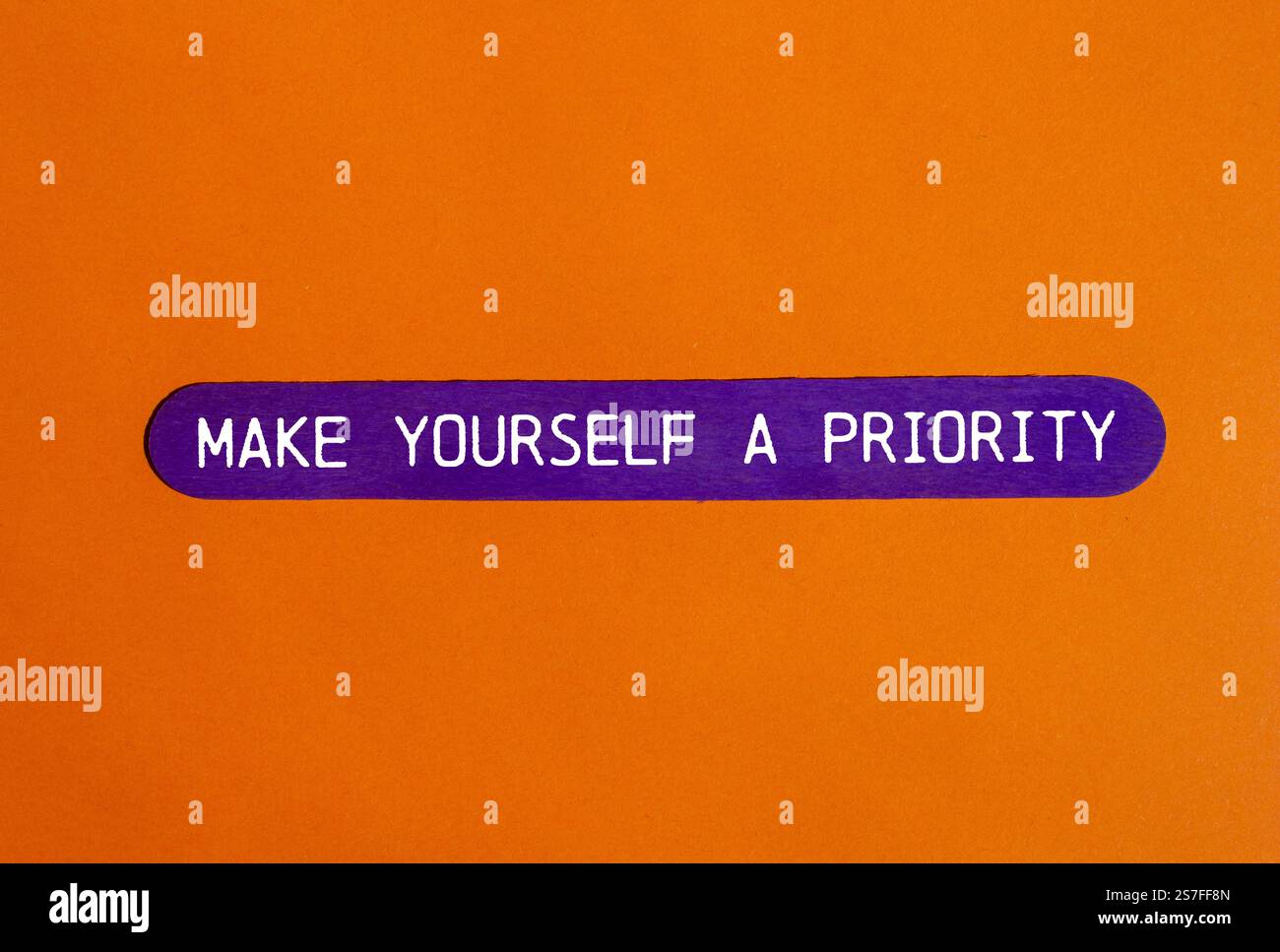 Faites-vous un message prioritaire écrit sur un bâton en bois violet avec fond orange. Conceptuel faites de vous un symbole de priorité. Copier l'espace. Banque D'Images