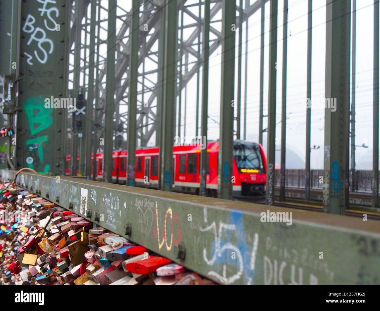 Un train régional conduisant vers la gare centrale de Cologne, Köln Hauptbahnhof (HBF) sur la Hohenzollernbrücke, avec les tristement célèbres cadenas d'amour vus sur le t Banque D'Images