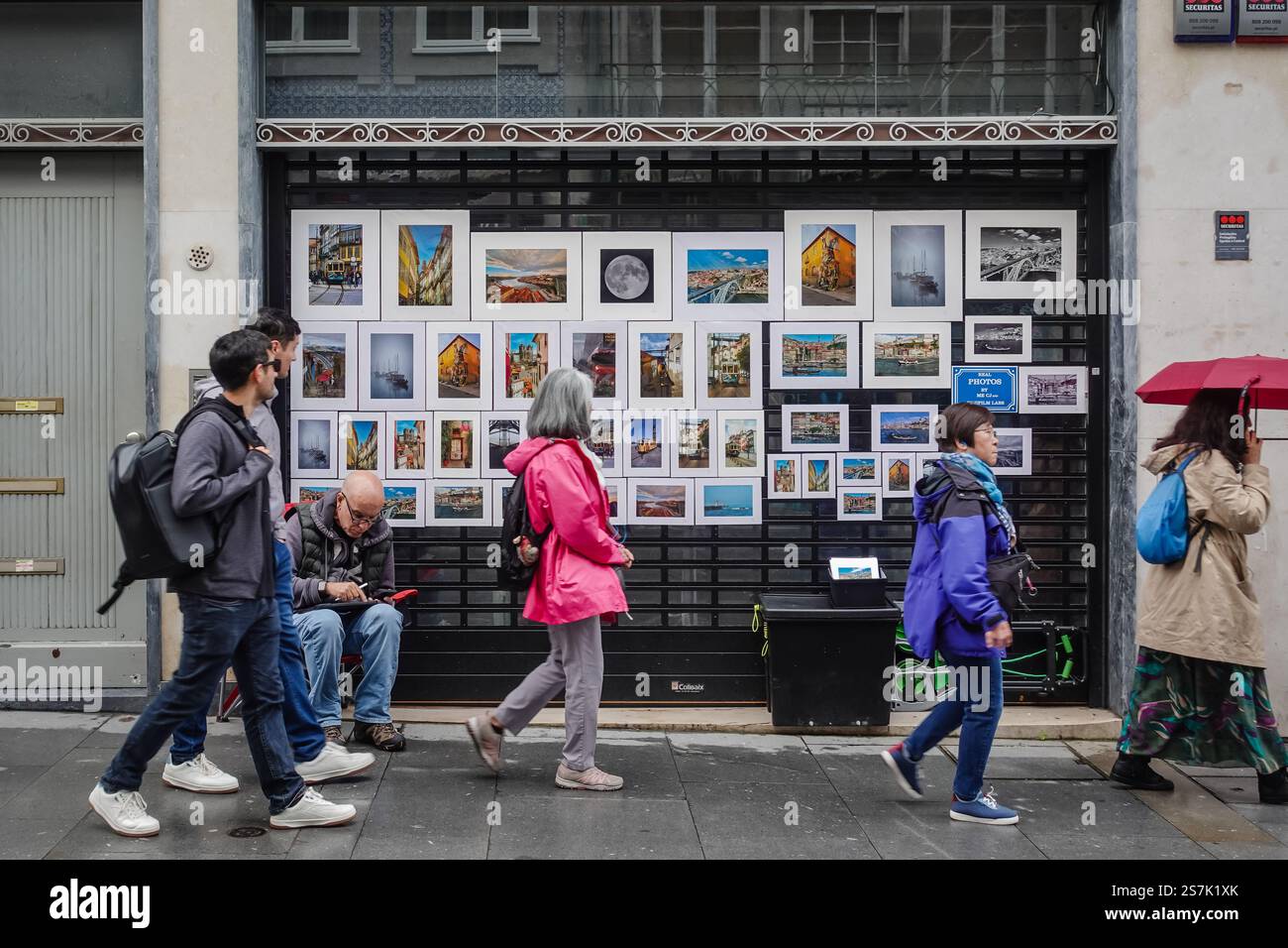 Un artiste visuel local met ses peintures en vente dans la rue à Porto, au Portugal, pendant que les visiteurs passent. Banque D'Images