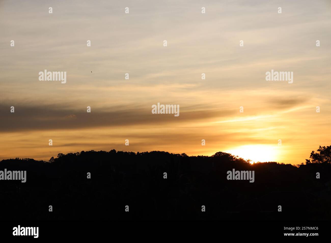 lever de soleil au-dessus de la forêt tropicale couverte collines peint de hauts nuages minces teintes pastel de rose orange or bleu gris mauve violet Banque D'Images